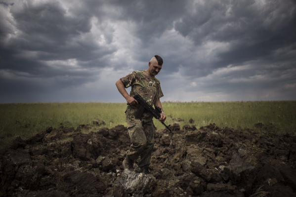 A Ukrainian serviceman investigates a crater left by a Grad rocket in the village of Toshkivka, (NW of Stanytsia Luhansk) in eastern Ukraine. Photo: Evgeny Maloletka. Source